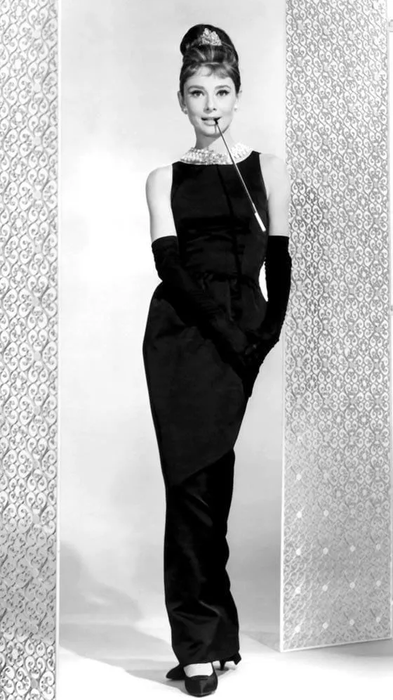 Audrey Hepburn de cuerpo entero con el vestido negro de Givenchy, guantes largos, collar de perlas y tiara